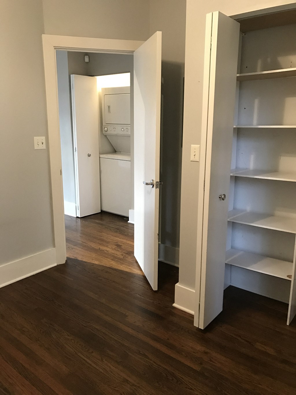 a bedroom with a closet and a hallway with shelves and a door to a bathroom
