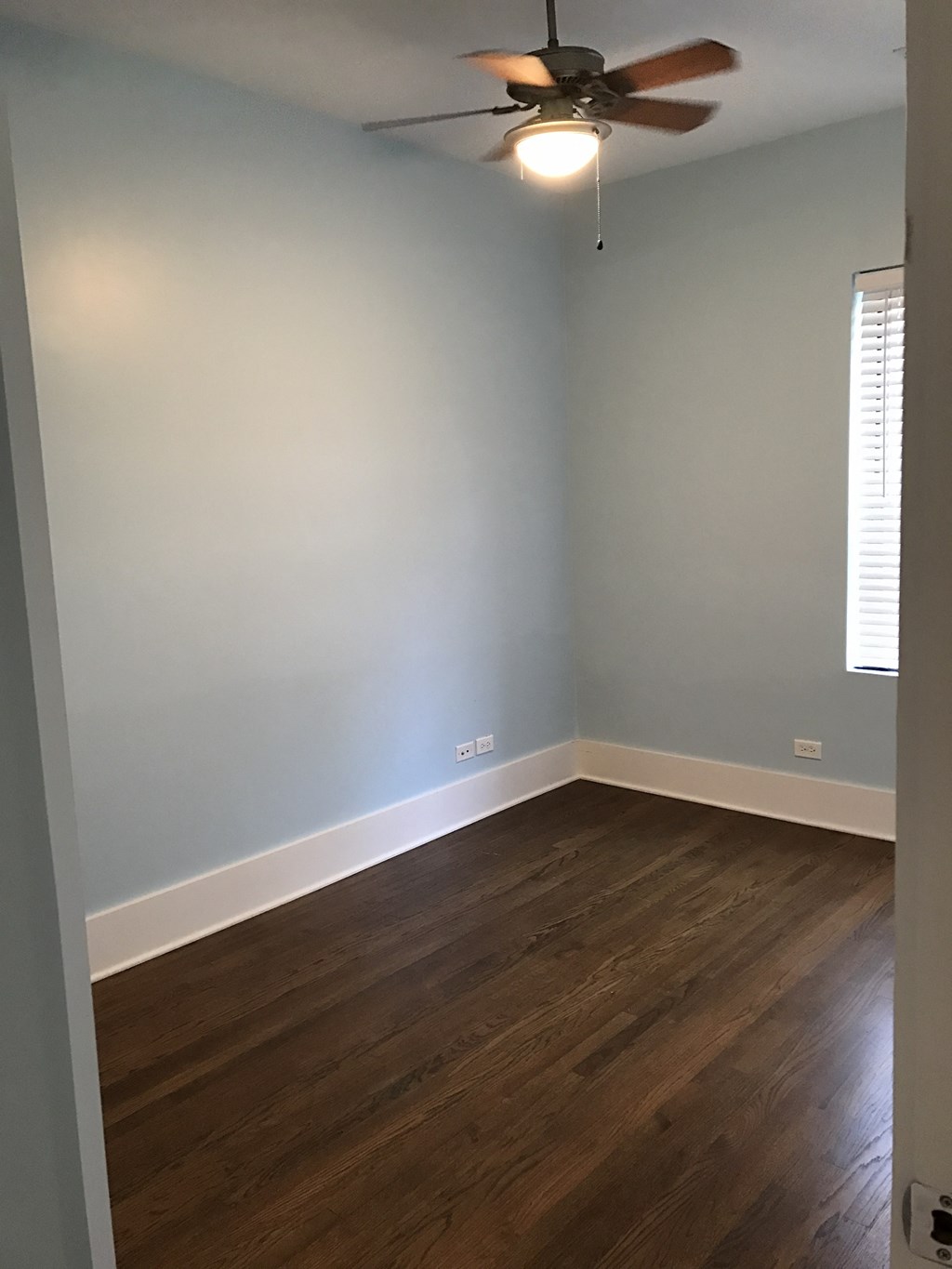an empty room with wooden floors and a ceiling fan