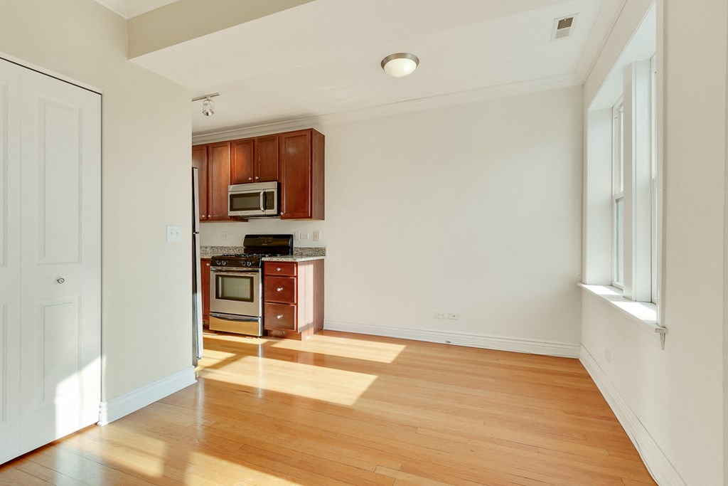 an empty living room and kitchen with wood flooring and