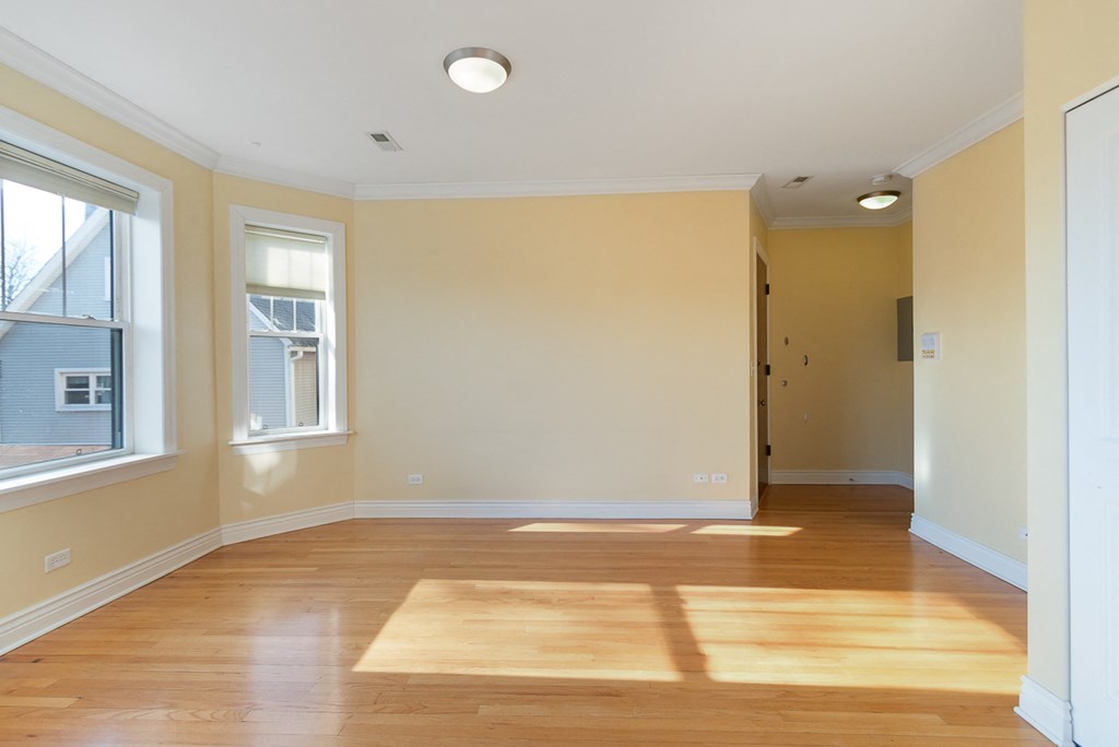 an empty living room with wooden floors and two windows