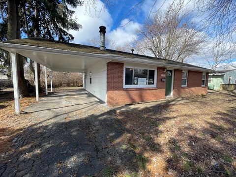 a brick house with a covered porch and a driveway
