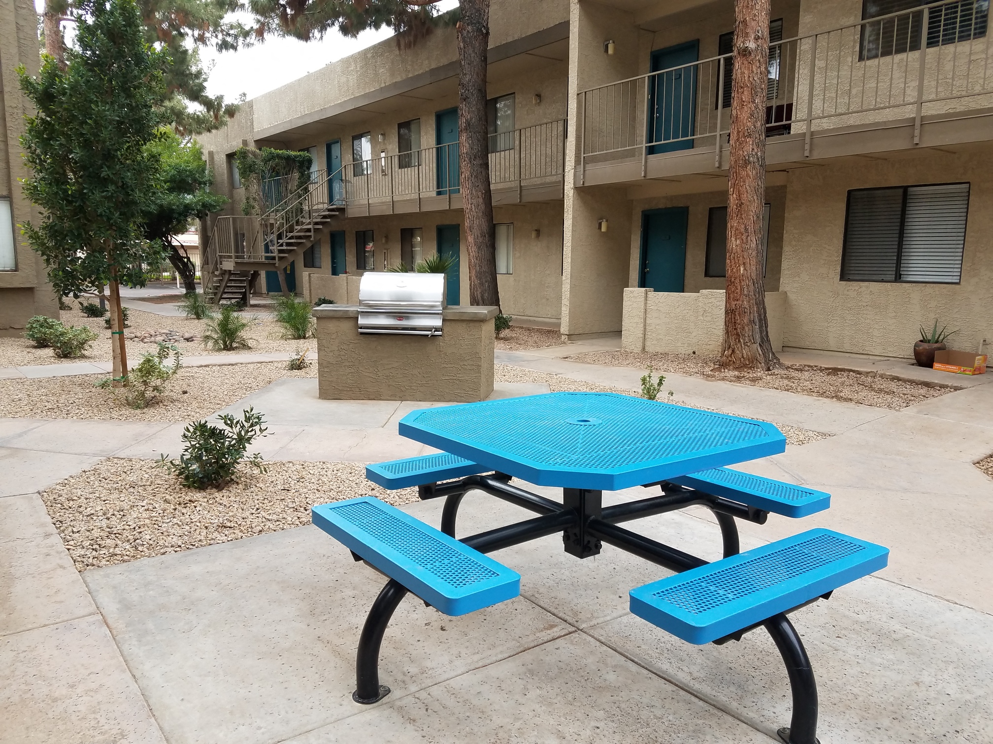 a picnic table with a grill in front of an apartment building
