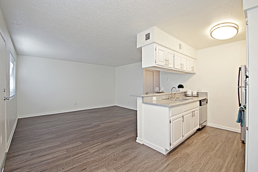 an empty kitchen and living room with a refrigerator and a sink