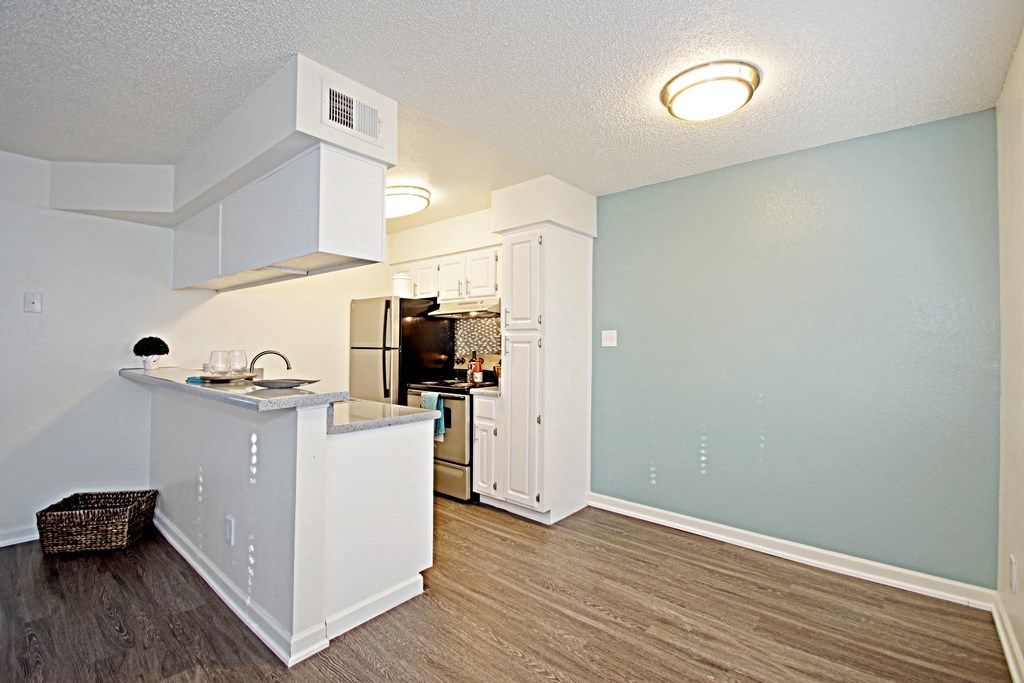 an open kitchen and living room with a counter and a refrigerator