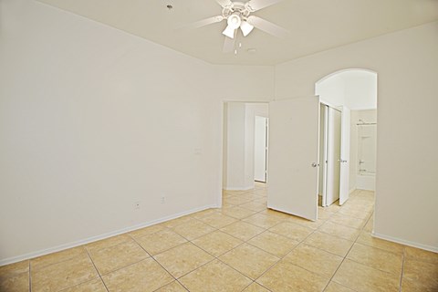 an empty living room with a ceiling fan and a tiled floor