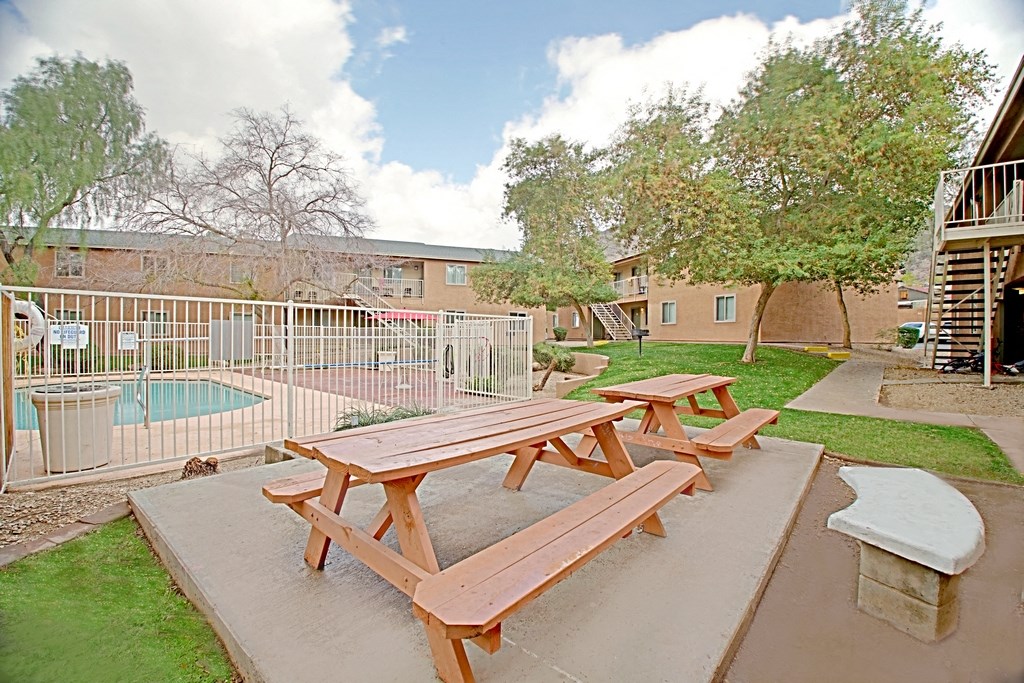 the picnic tables in the courtyard of an apartment building with a pool
