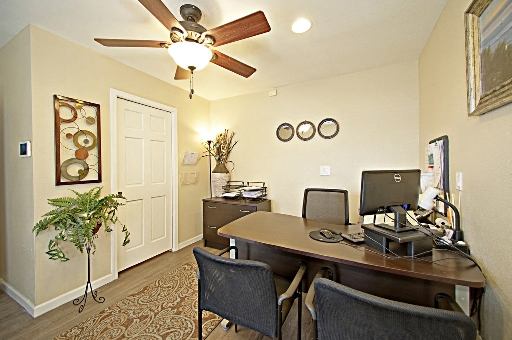 a home office with a ceiling fan and a desk with a computer