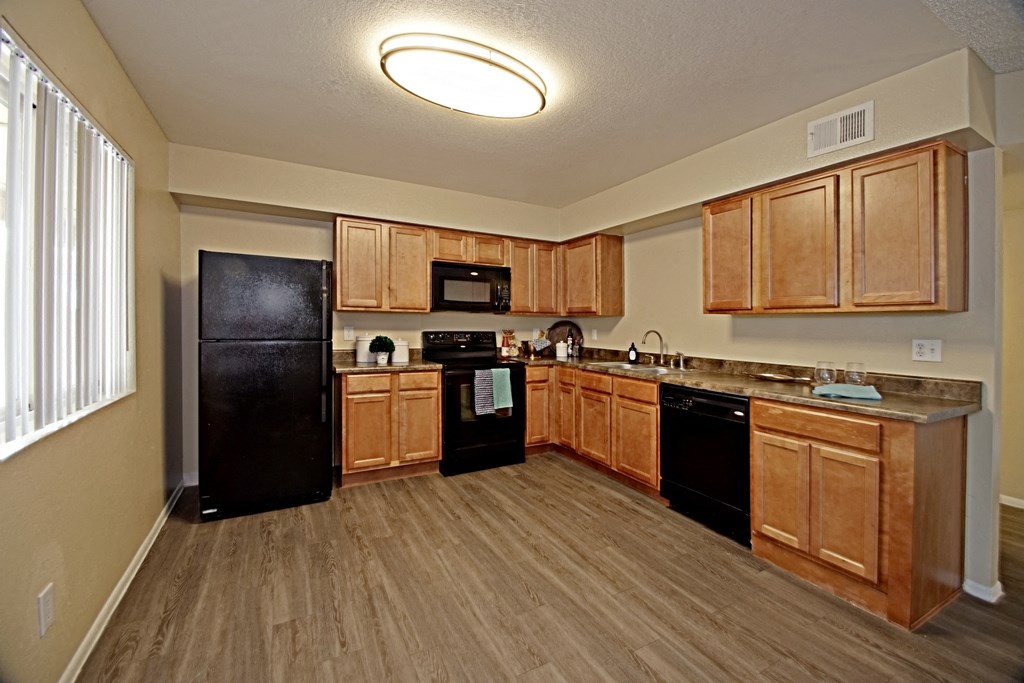a kitchen with wooden cabinets and a black refrigerator