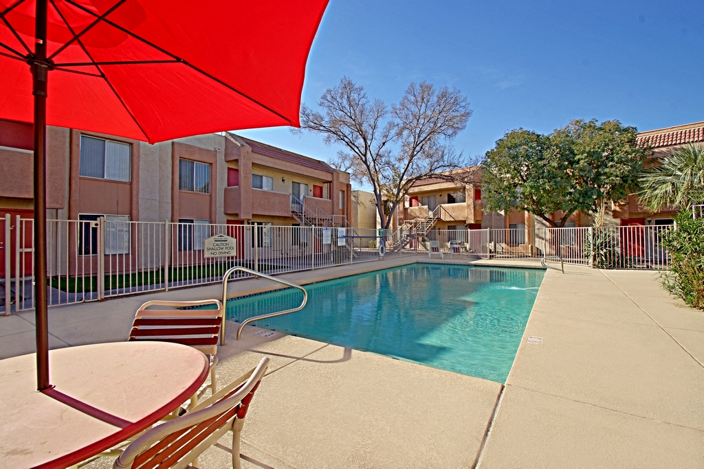 our apartments have a swimming pool and a patio with chairs and an umbrella