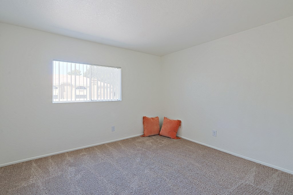 an empty room with two orange pillows on the floor and a window in the