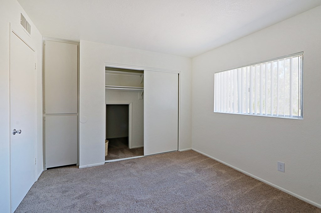 an empty room with a door to a closet and a window