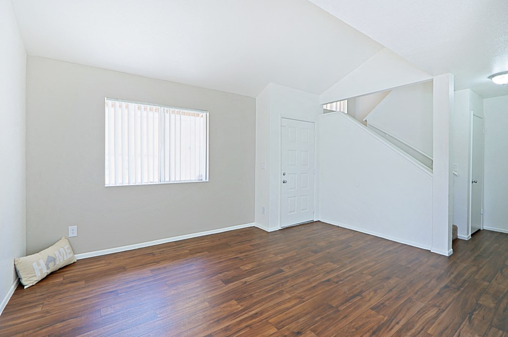 an empty living room with hardwood floors and a window