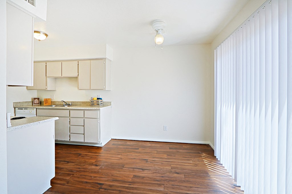 an empty kitchen with white cabinets and a wood floor
