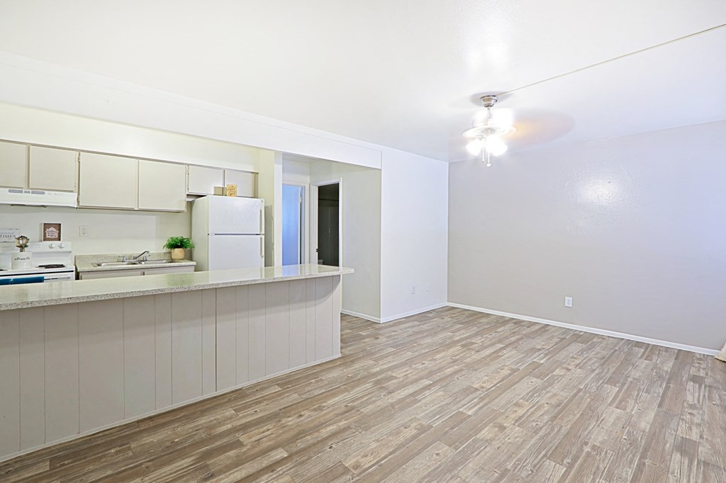 the living room and kitchen of an apartment with wood flooring