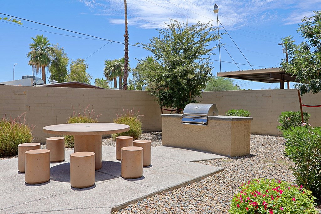 a patio with a table and stools and a grill