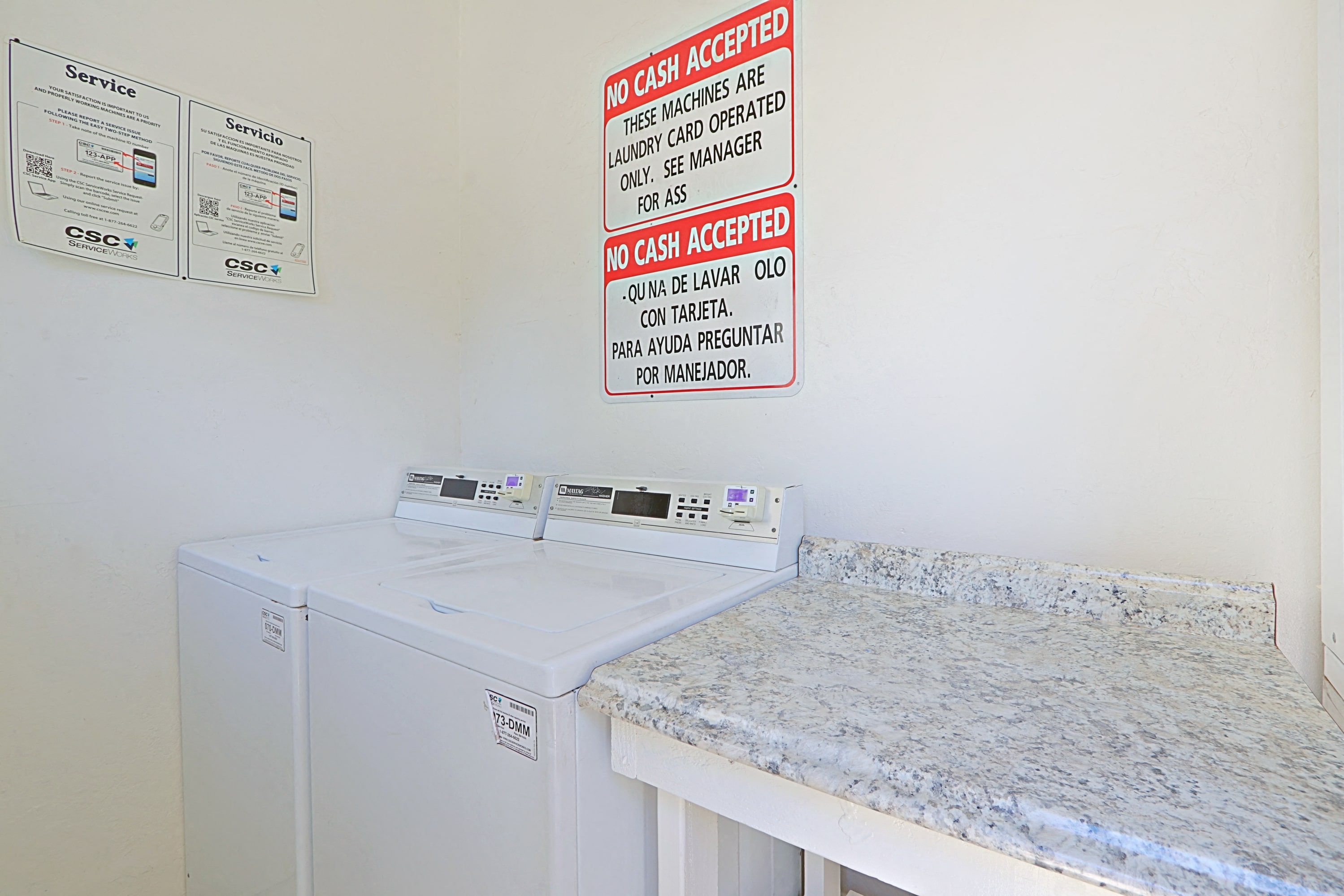 a laundry room with two washing machines and a counter with a sign on the wall