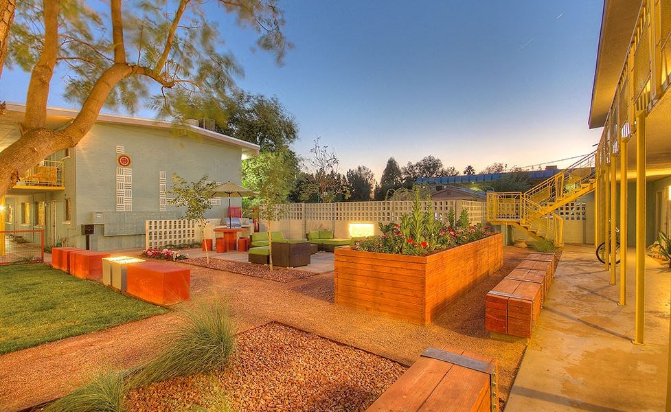 a backyard with benches and a tree and a house