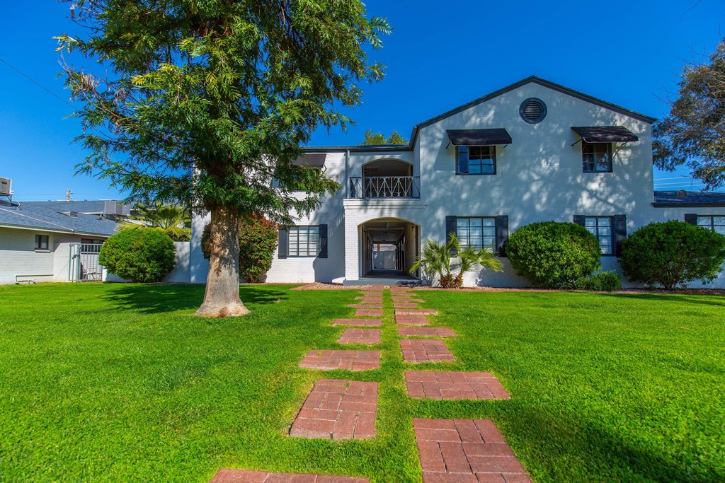 a large white house with a lawn and tree in front of it