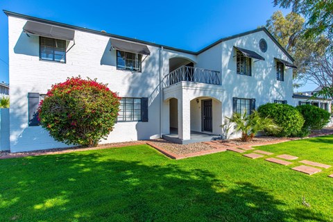a white house with a lawn and a balcony