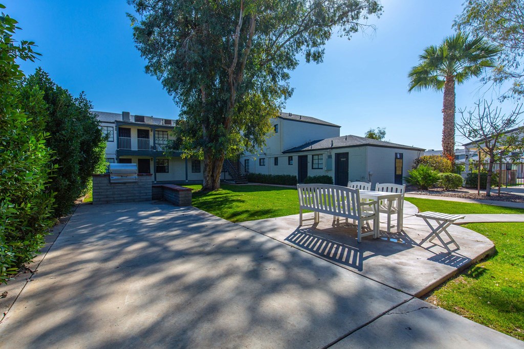 a patio with a table and chairs in front of a house