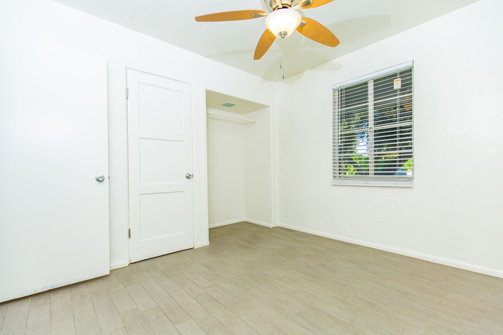 an empty room with a ceiling fan and a window