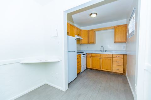 an empty kitchen with wooden cabinets and a white refrigerator