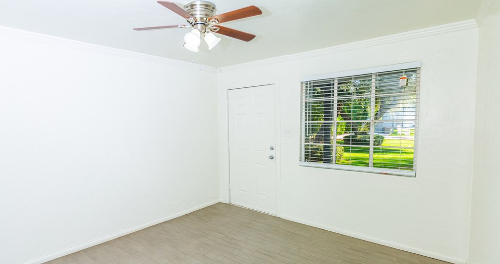 an empty room with a window and a ceiling fan