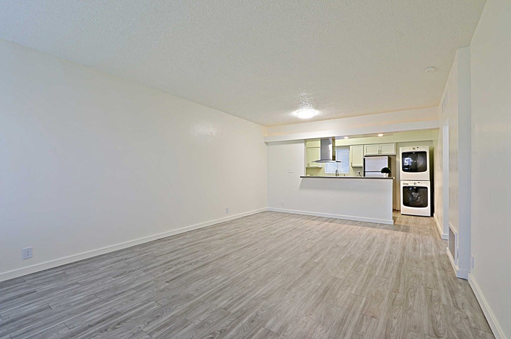 the living room and kitchen of an empty apartment with wood flooring