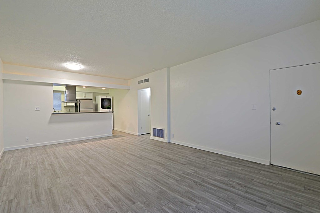 the living room and kitchen of a new home with white walls and wood flooring