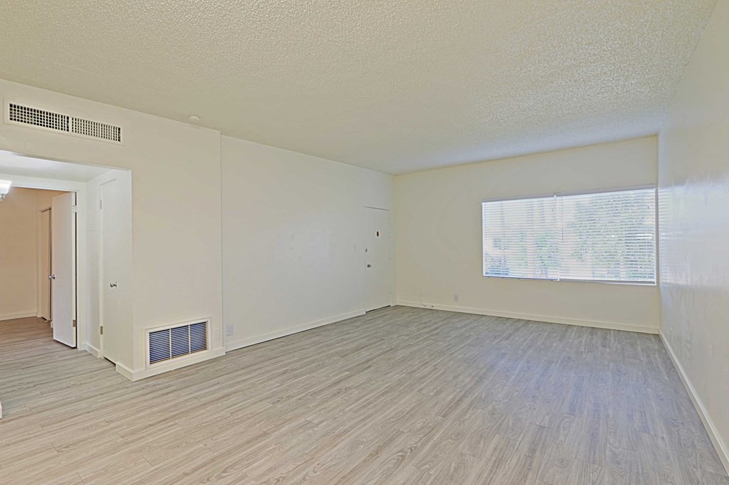 an empty living room with a wood floor and a window