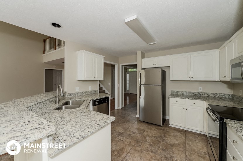 a kitchen with granite counter tops and a stainless steel refrigerator