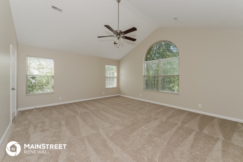 the spacious living room with carpeting and a ceiling fan