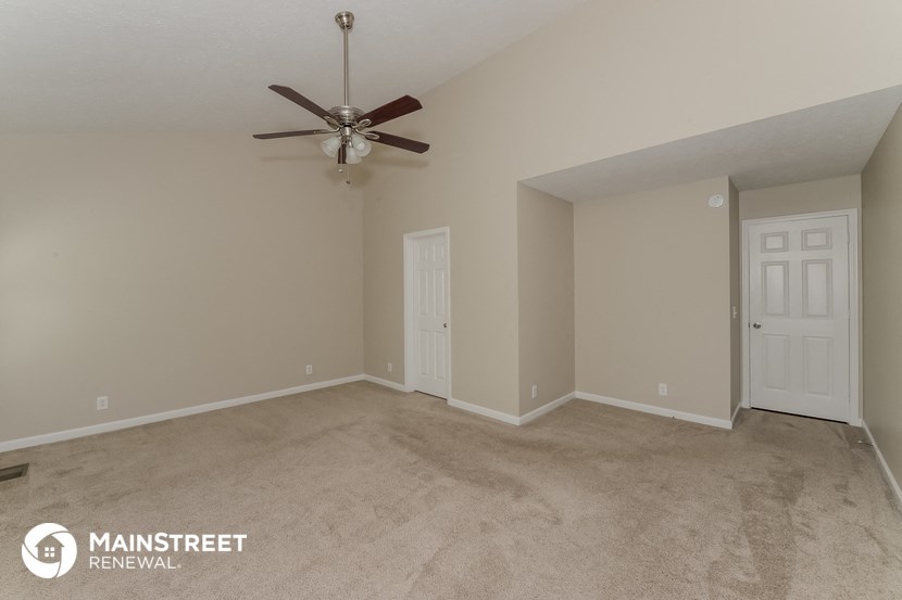 the spacious living room with carpeting and a ceiling fan