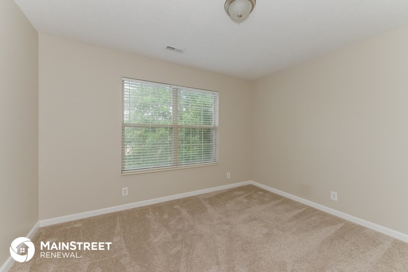 the spacious living room with a large window and beige carpet