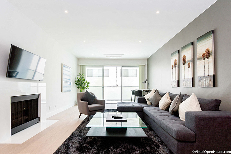 a contemporary living room with a gray couch and a glass coffee table