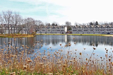 A lake with a building in the background and dry grass in the foreground.