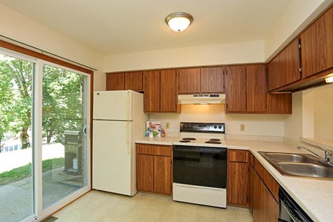A kitchen with a white refrigerator and wooden cabinets.