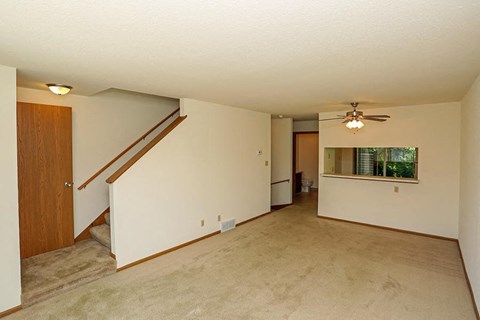 A room with a staircase and a ceiling fan.