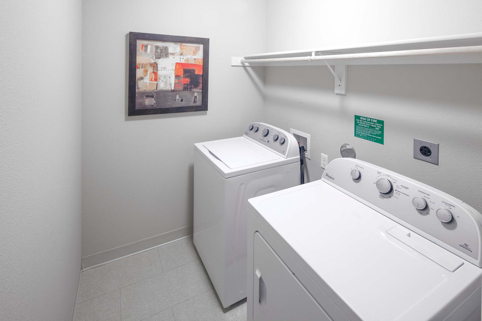 a white laundry room with two washes and a dryer