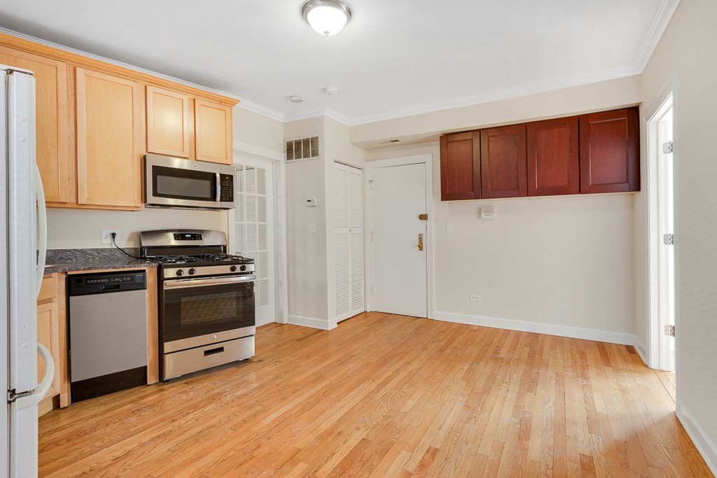 an empty kitchen with wood flooring and a stove and microwave