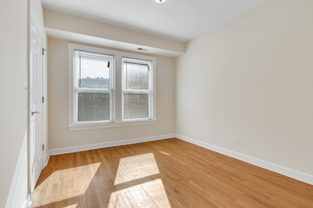 an empty living room with hardwood floors and two windows