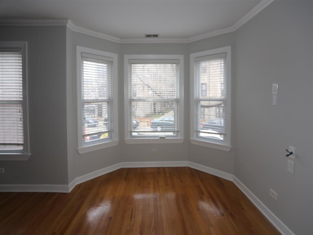 a living room with a wooden floor and four windows