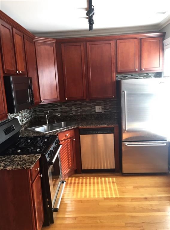 a kitchen with wooden cabinets and a stainless steel refrigerator