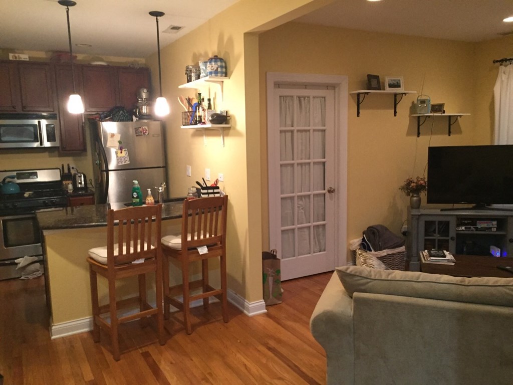a kitchen with a bar and a living room with a couch and a tv