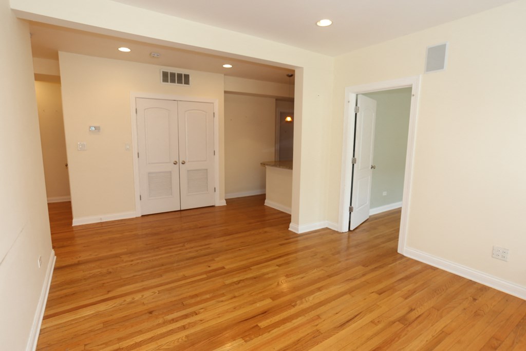 an empty living room with wood flooring and a closet