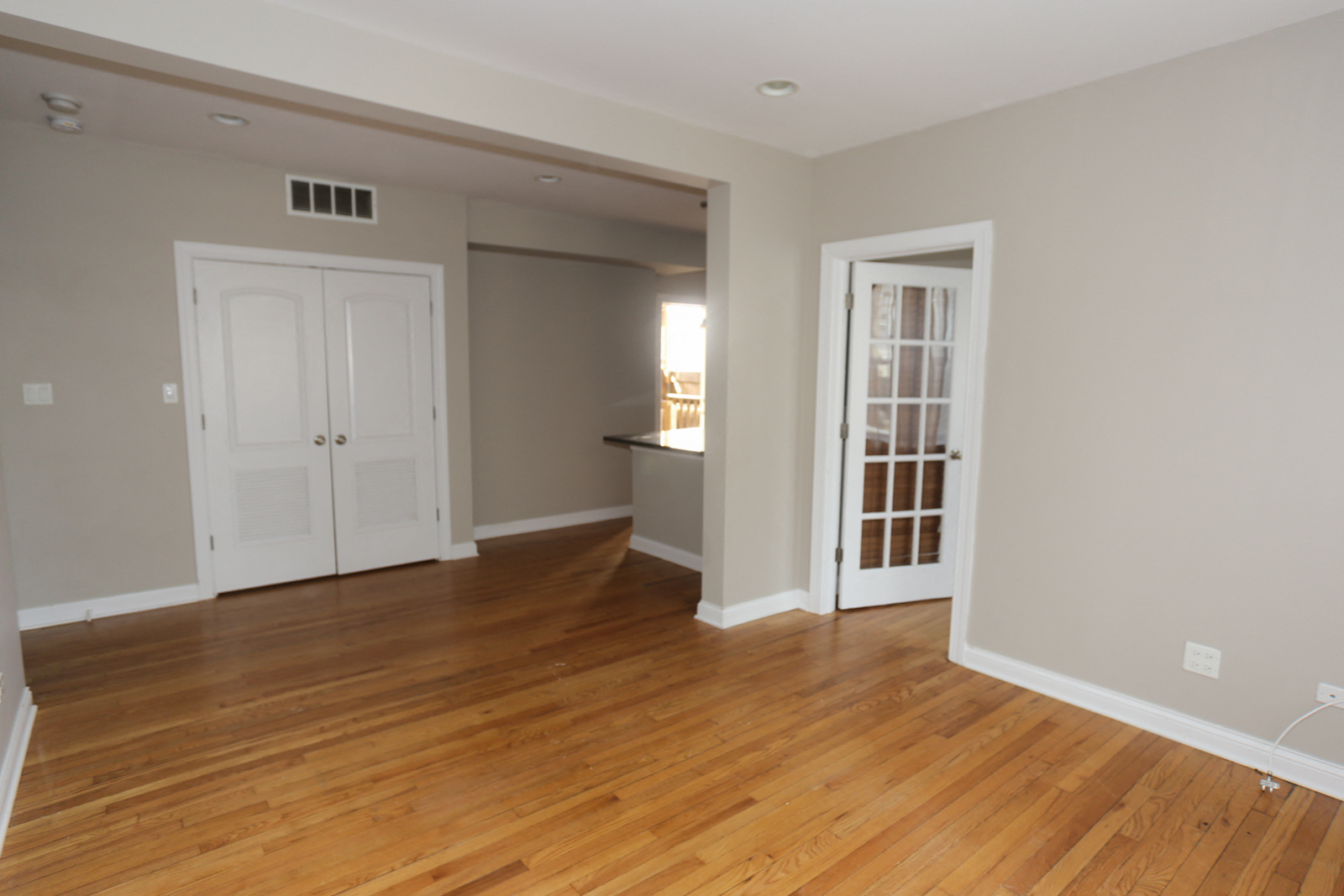 an empty living room with wooden floors and white doors