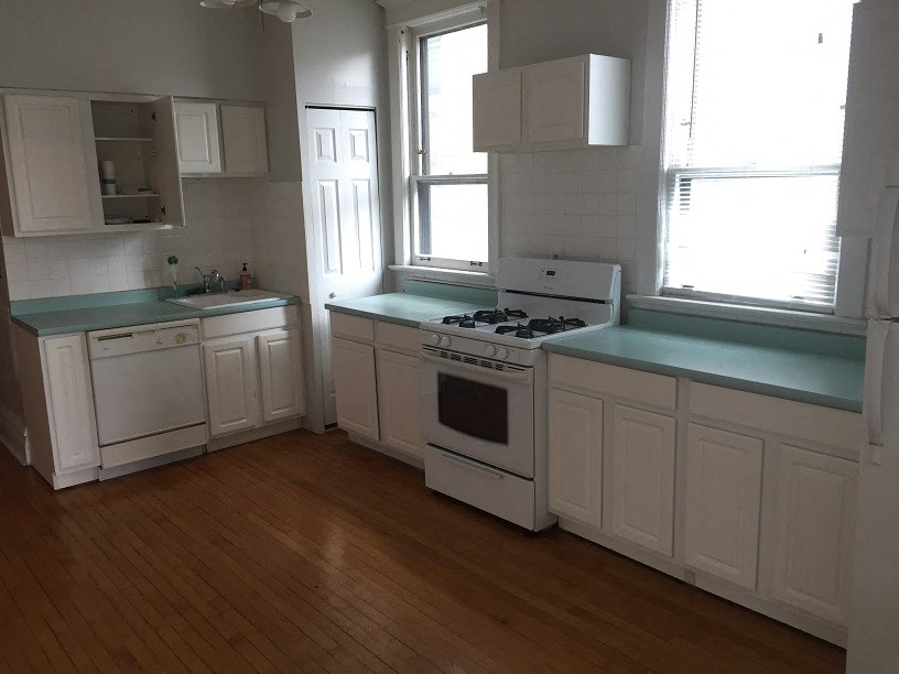 a kitchen with white cabinets and a stove and a window