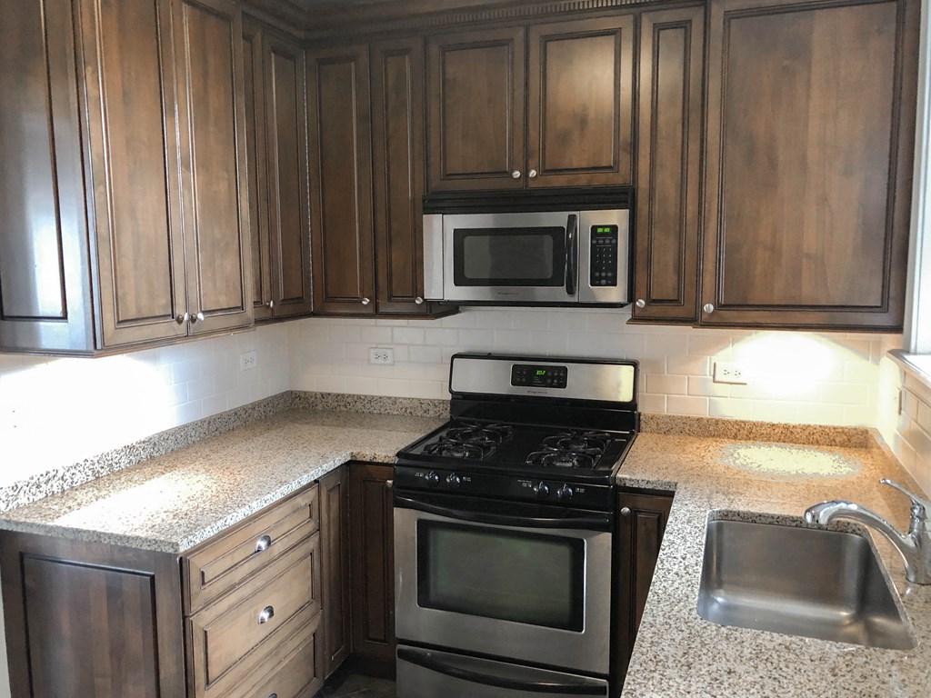 an empty kitchen with wooden cabinets and stainless steel appliances