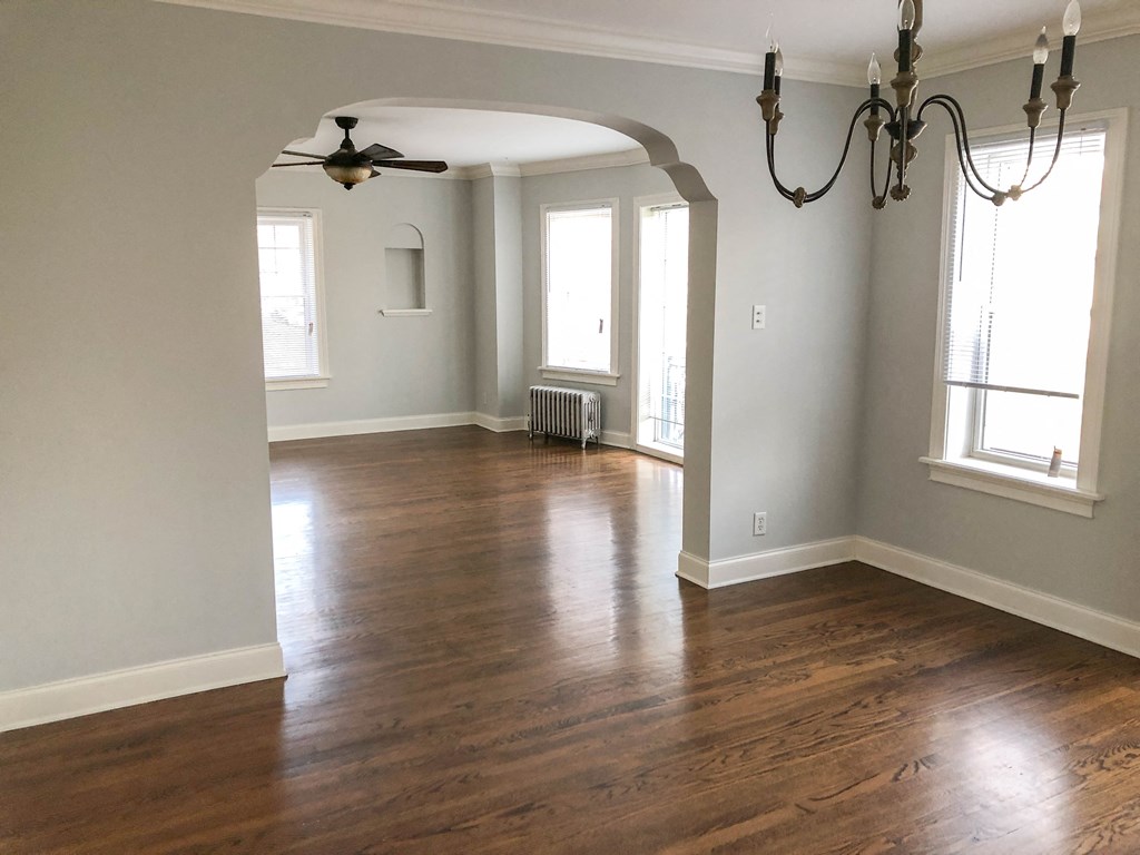 an empty living room with hard wood floors and a chandelier