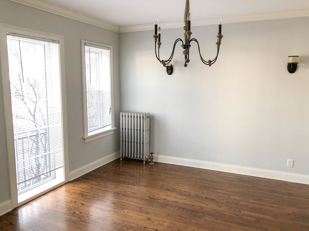 an empty living room with a radiator and a chandelier